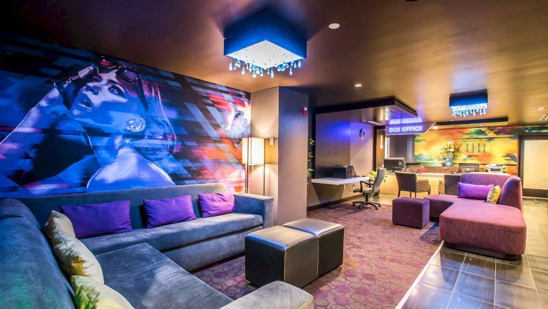 A hotel lobby with a large mural, seating area, and box office.