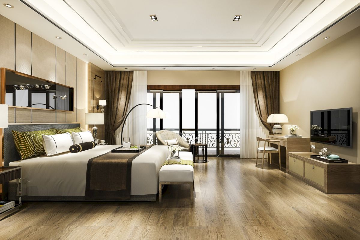 A wide view of a hotel room with a large bed, balcony, desk, TV, and sofa.