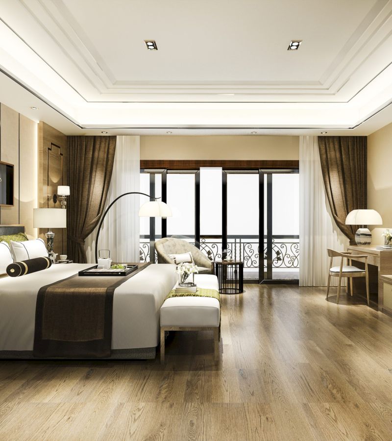 A wide view of a hotel room with a large bed, sofa, desk, and balcony.