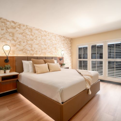 A wide view of a hotel room with a large bed, nightstands, and a window.