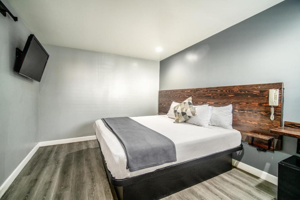 A hotel room with a large bed, wooden headboard, and mounted TV.