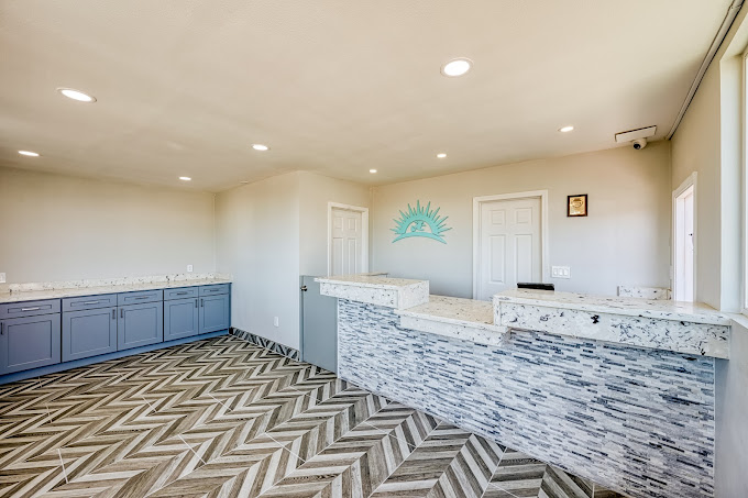 A modern hotel lobby with a marble front desk, gray cabinets, and a chevron-patterned floor.